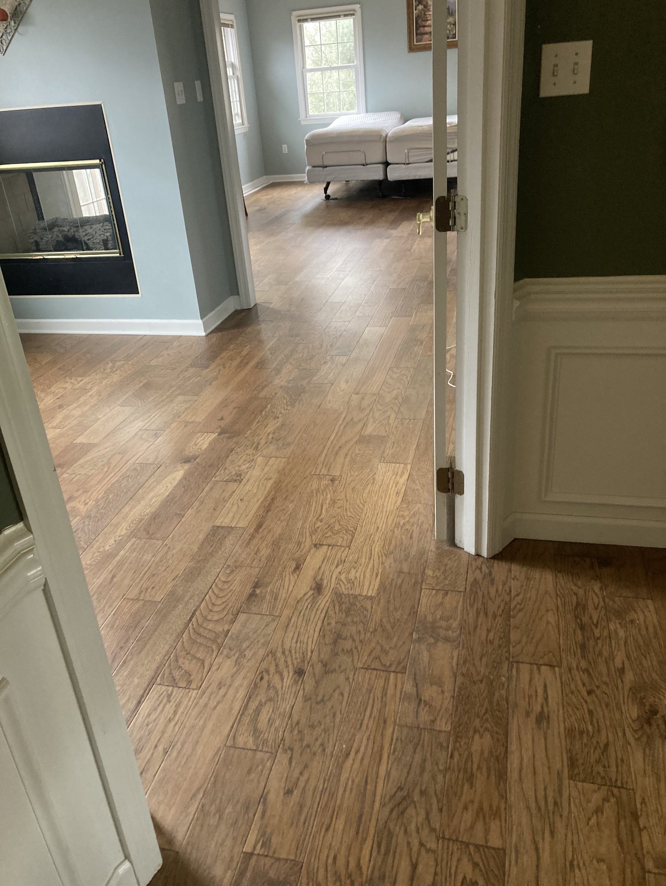 Hand-scraped hardwood planks running from a hallway into a bedroom